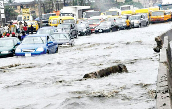 Residents wade through floodwaters during Lagos flooding on a submerged street in Festac.